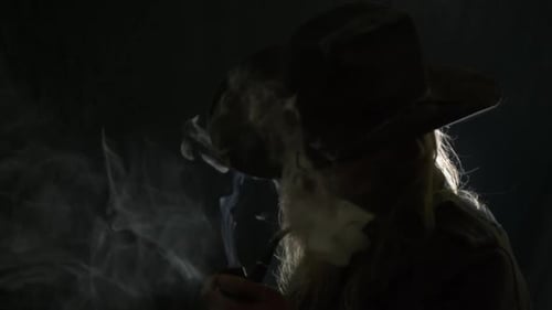 Man with Hat Smokes Pipe in Dark