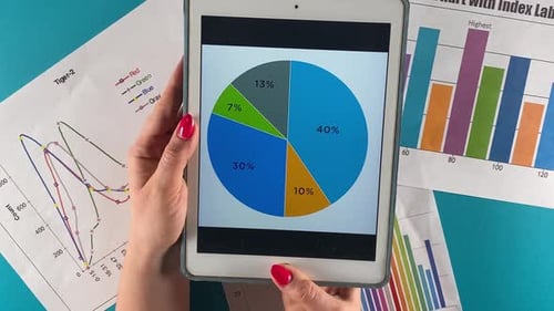 Tablet Displays Pie Chart over Printed Graphs