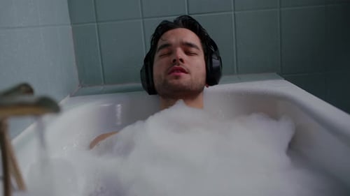 Man Listening to Music Relaxing in a Bubble Bath