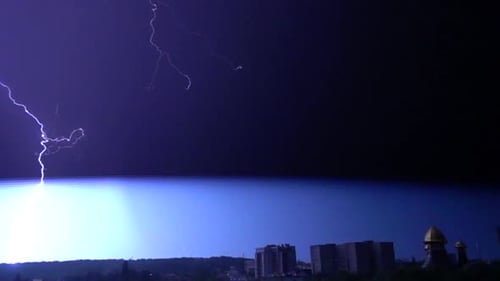 Flashes of lightning in the night sky among thunderclouds.