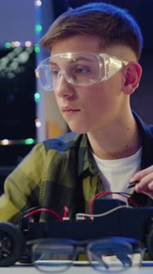 Teen Boy Builds Robot Car Wearing Safety Glasses
