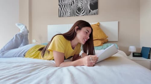 Woman Lying on Bed Writing in Notebook