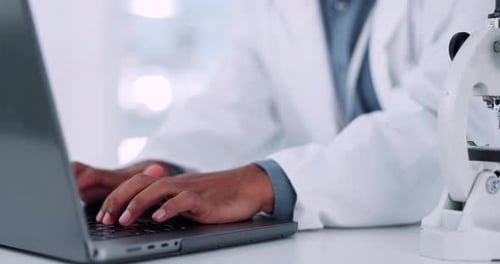 Scientist Typing Data on Laptop in Laboratory
