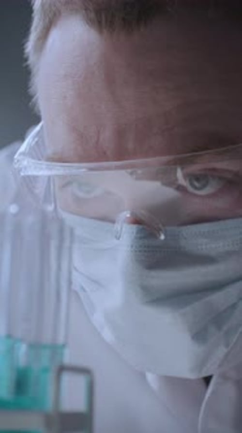 Male Scientist in Face Mask Analyzing Chemical Samples in Test Tubes