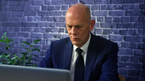 A mature business man working on a laptop computer at night on a dark office