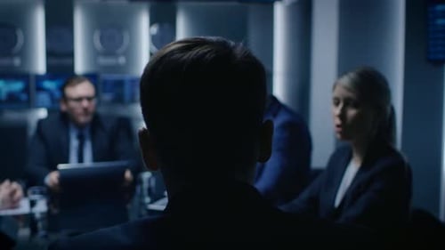 People in Suits Sit at Conference Table