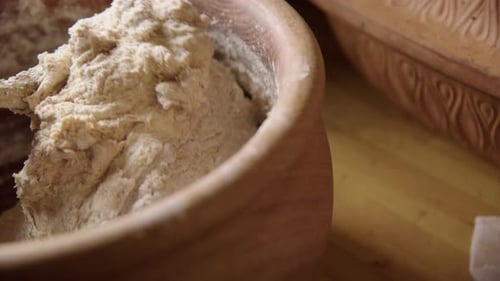 BAKING - Wooden spoon mixing sourdough bread dough, turning bowl, slow motion