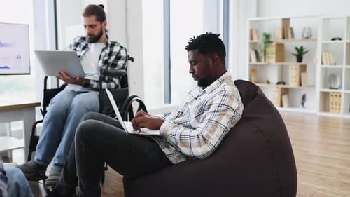 Diverse Coworkers Collaborating in a Modern Office with Laptops and Focus