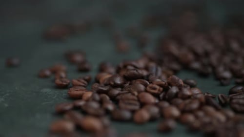 Dolly right of coffee beans lying on the dark green background
