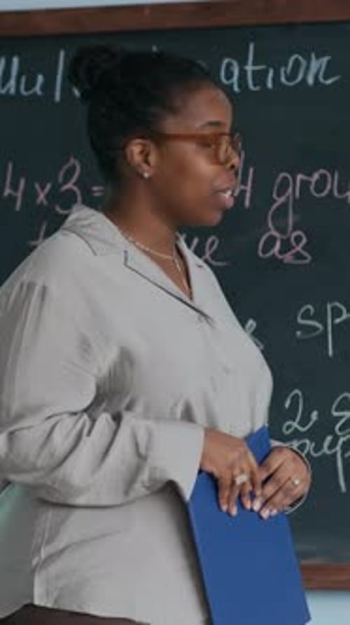 Teacher Explains Math Problem at Chalkboard