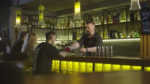 A Bartender Serves Customers By Placing a Cocktail on the Bar Counter