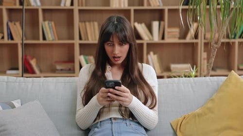 Woman Reacting to Phone With Surprise Indoors
