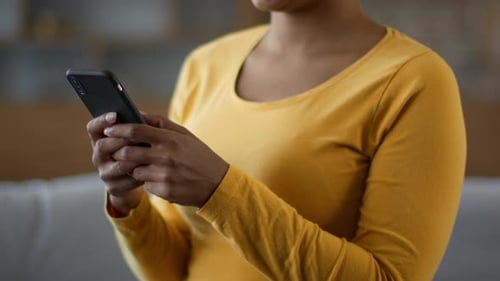 Unrecognizable Young Black Woman Web Surfing on Smartphone Chatting with Friend or Reading News