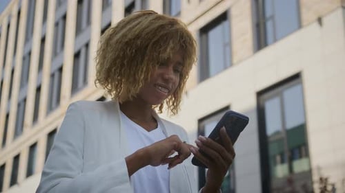 Woman Using Smartphone in Front of Modern Building