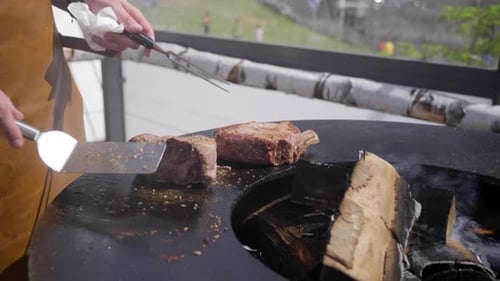Chef cooking juicy beef steak on open fire barbecue grill