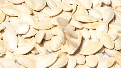 Top View of Dry Pumpkin Seeds Falling Into a Plate