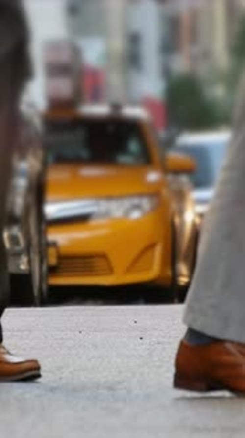 A Busy Urban Street Featuring a Yellow Taxi in Clear Focus Amidst the City Bustle
