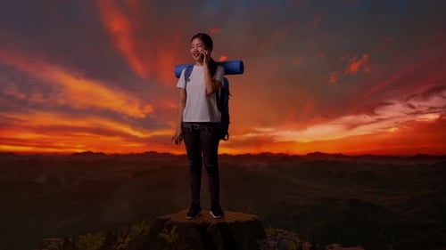 Female Hiker Smiling And Talking On Smartphone On The Top Of Mountain