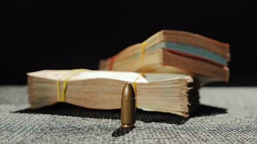 Bullet standing in front of money stacks as symbol of war economy and conflict