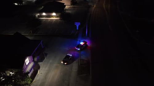 Un coche de policía detiene un coche negro en la carretera estadounidense. Toma aérea de arriba hacia abajo. Luz azul y roja parpadeante