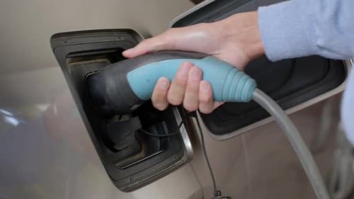 Laden eines Elektroautos mit Stromkabel, das an den Ladeanschluss des Fahrzeugs angeschlossen ist, in der Garage