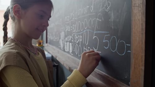 Mädchen schreibt Robotik-Programmiercode auf Tafel im Stem-Kurs