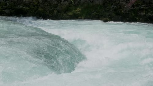 A waterfall with a large amount of water on a clean and wild mountain river. Close-up shot of water