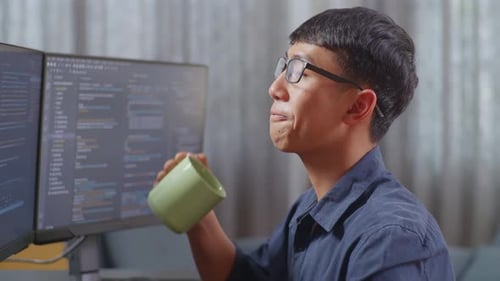 Programmer Drinking From Mug and Typing on Keyboard