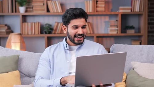 Happy Indian Man is Using a Laptop for a Video Conference in His Home Office