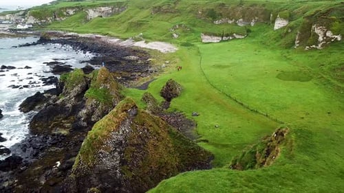 Revealing drone shot of coastline in Northern Ireland with people