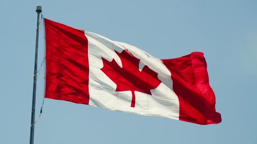 Canadian Flag Waving Against Blue Sky