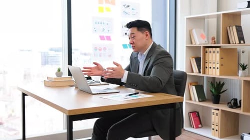 Asian Businessman Engaging in Online Video Call in Modern Office