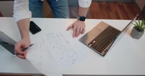 Top View. Man Hands which Holding Pen Drawing Lines on Large Paper Format Scheme Working at the Tab