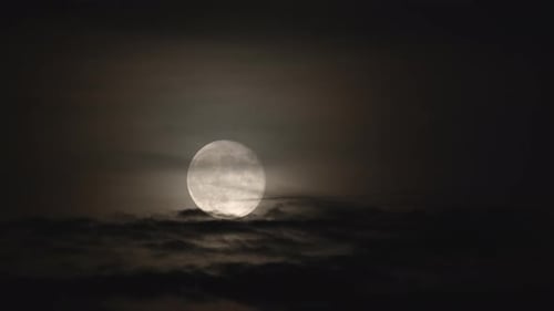 Full Moon Shining Behind Dark Swirling Clouds