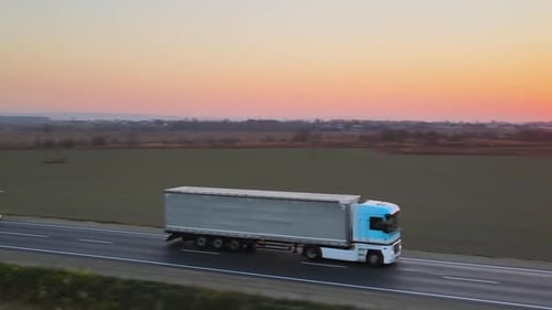 Aerial View of Semitruck with Cargo Trailer Driving on Highway Hauling Goods in Evening
