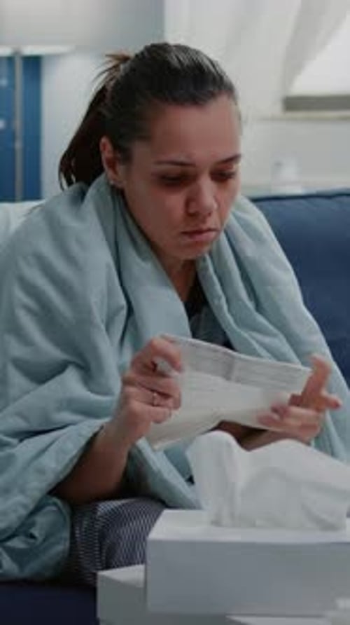 Woman Reading While Sick and Wrapped in Blanket