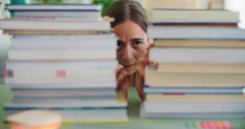 A Student Terrified By the Amount of Studying Pushes Aside a Stack of Books