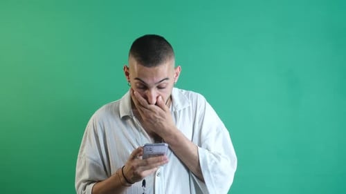 Concerned Man Looks at Smartphone Against Green Screen