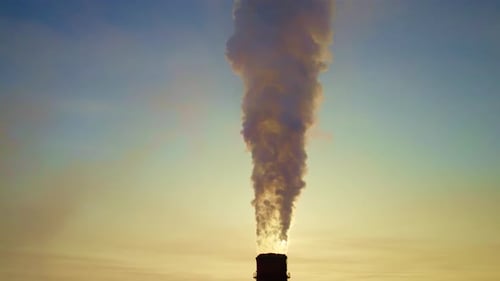 Industrial Smokestack Emits Thick Smoke During Sunset at a Power Plant in an Urban Area
