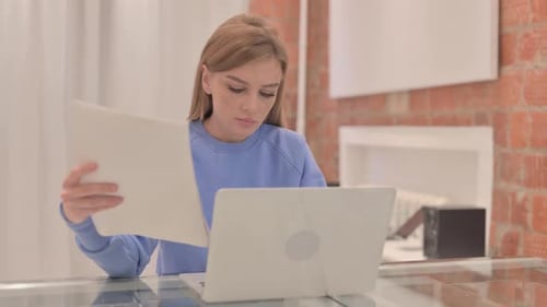 Young Woman Working at Laptop with Documents