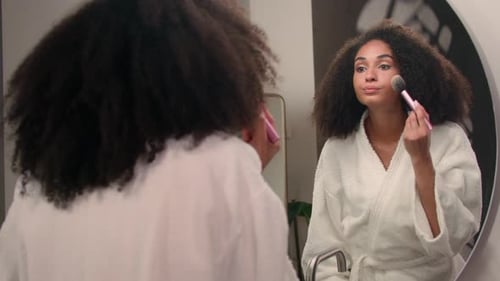 Woman Applying Makeup in Bathroom Mirror
