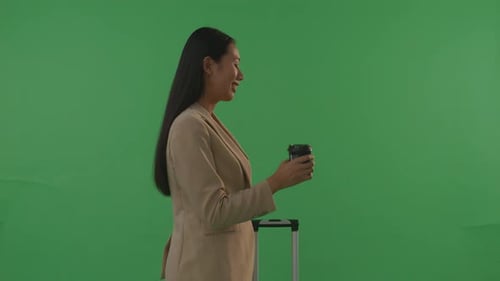 Side View Businesswoman Traveler With Luggage Drinking Coffee While Standing In The Green Screen