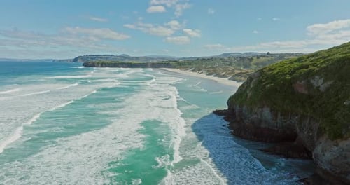 Scenic aerial view over ocean with rolling white wash waves, white sandy beach and sand dunes at Sma