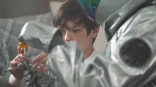 Boy Plays With Solar System Model Beside Astronaut