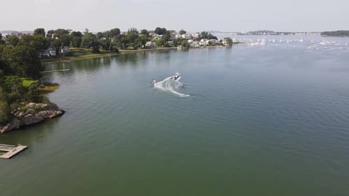 Flying Towards A Water Skier Towed By A Speedboat Across Cohasset Harbor In Massachusetts. aerial dr