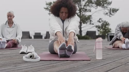 Diverse Adult Women Performing Stretching Exercise during Outdoor Workout