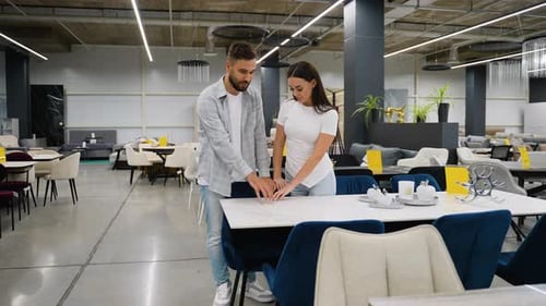 Young Couple Choosing Dining Table in Furniture Showroom