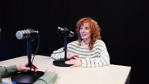 Podcast Host Smiling and Talking Into Microphone