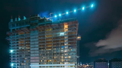 Construction Crane Working on Construction Development Site Area at Night Time