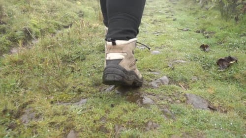 Close up slow motion shot of hiking boots walking down the path